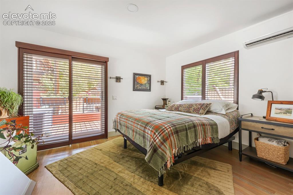 Image 18 of 30: Hardwood flooring, sliding glass door with horizontal blinds, built-in wall