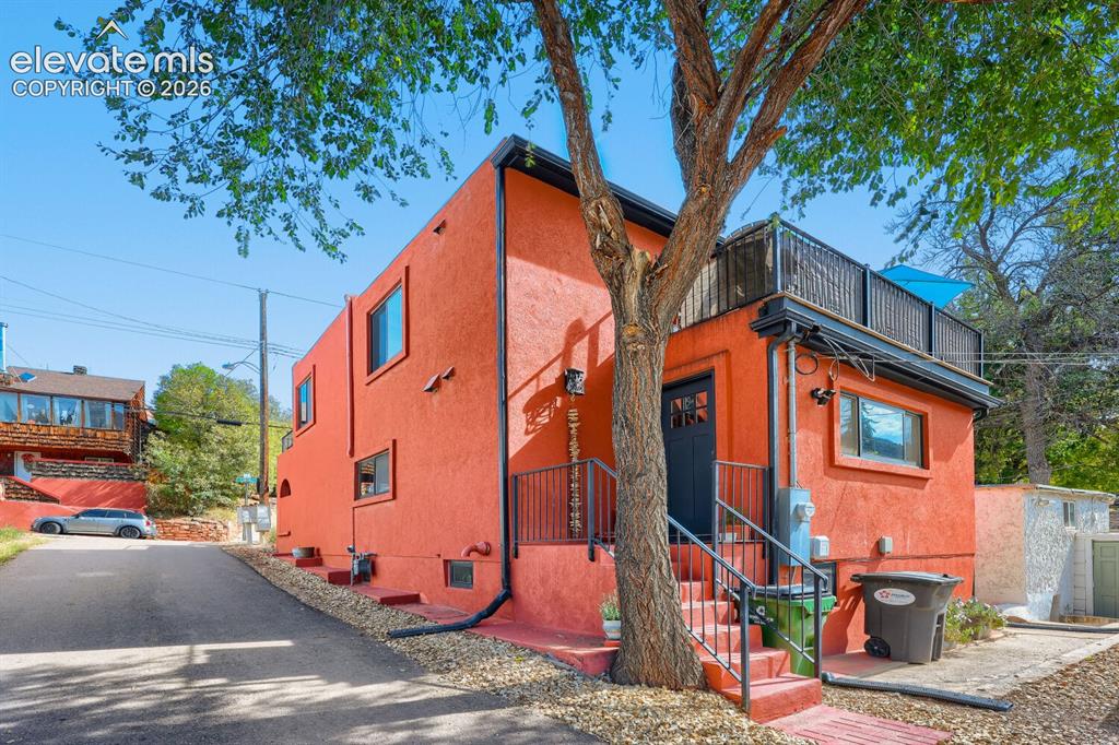 Image 2 of 30: Stucco exterior with multiple windows, leading to an upper-level balcony wi