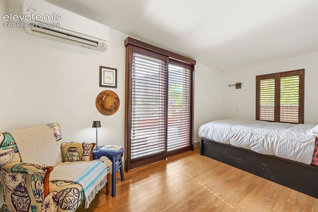 Image 20 of 30: Wood-finish flooring, wall-mounted air conditioning unit, and wood-framed g