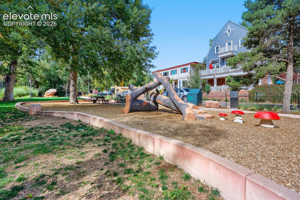 Image 27 of 30: Landscaped outdoor area featuring natural wood play elements, decorative mu