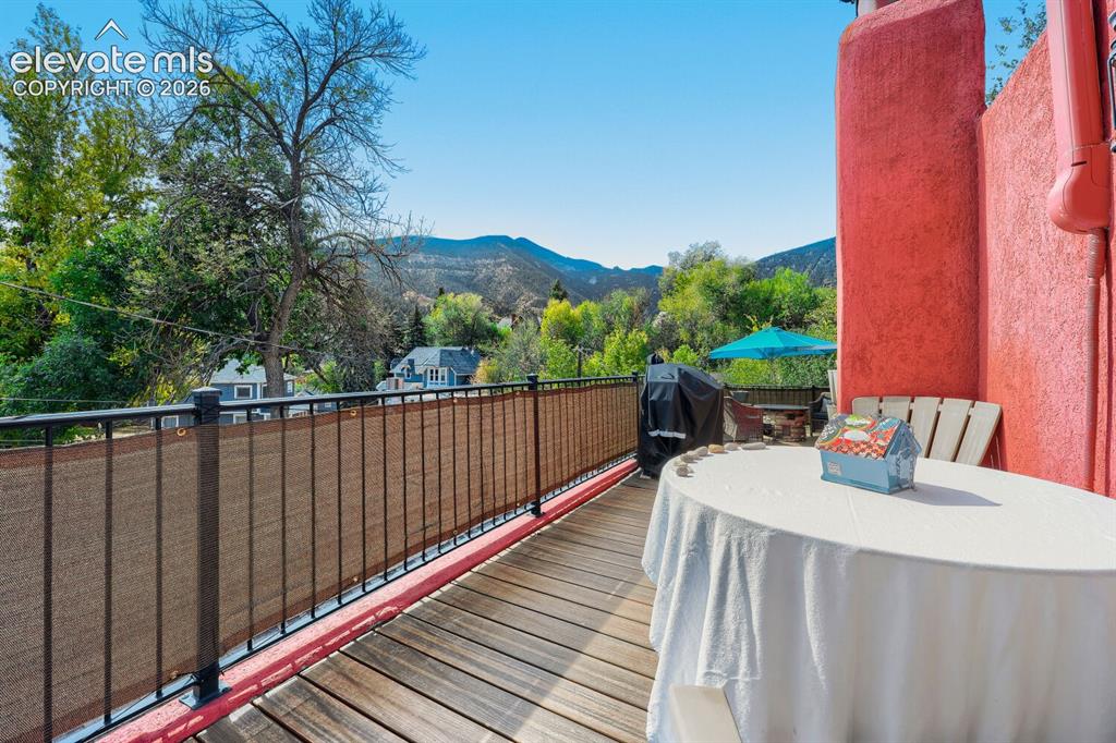 Image 5 of 30: Wood-finish decking with a black metal railing and privacy screening