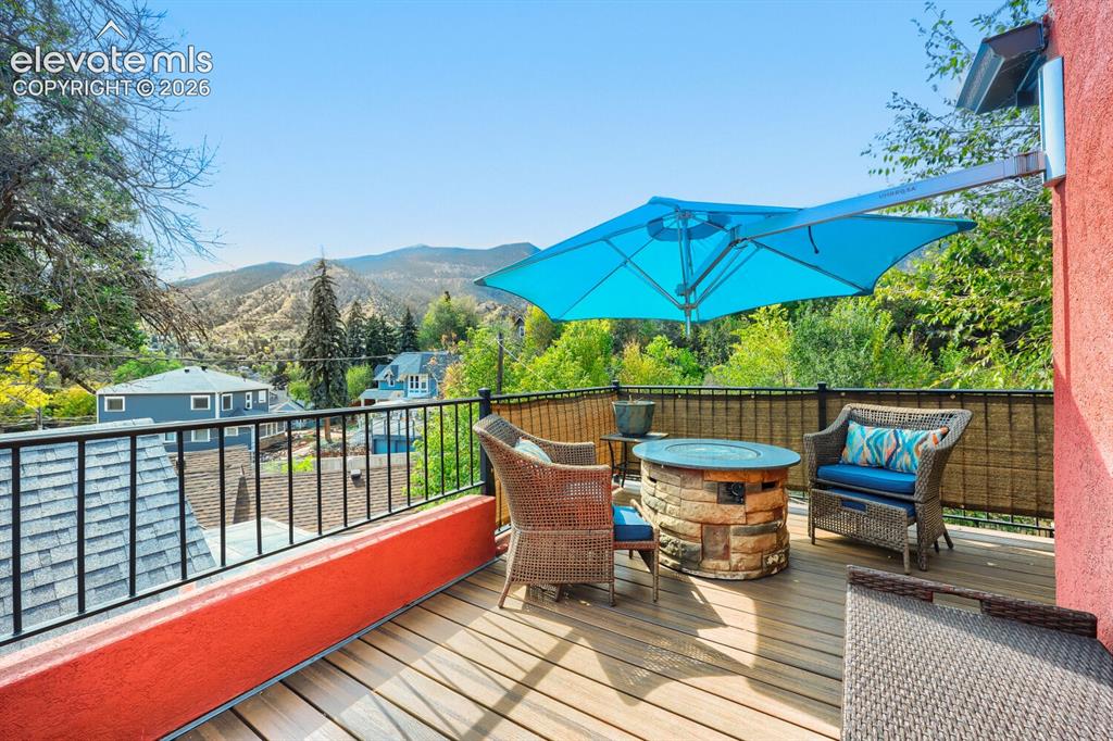 Image 6 of 30: Expansive outdoor deck featuring wood-finish flooring, a stone-clad fire pi