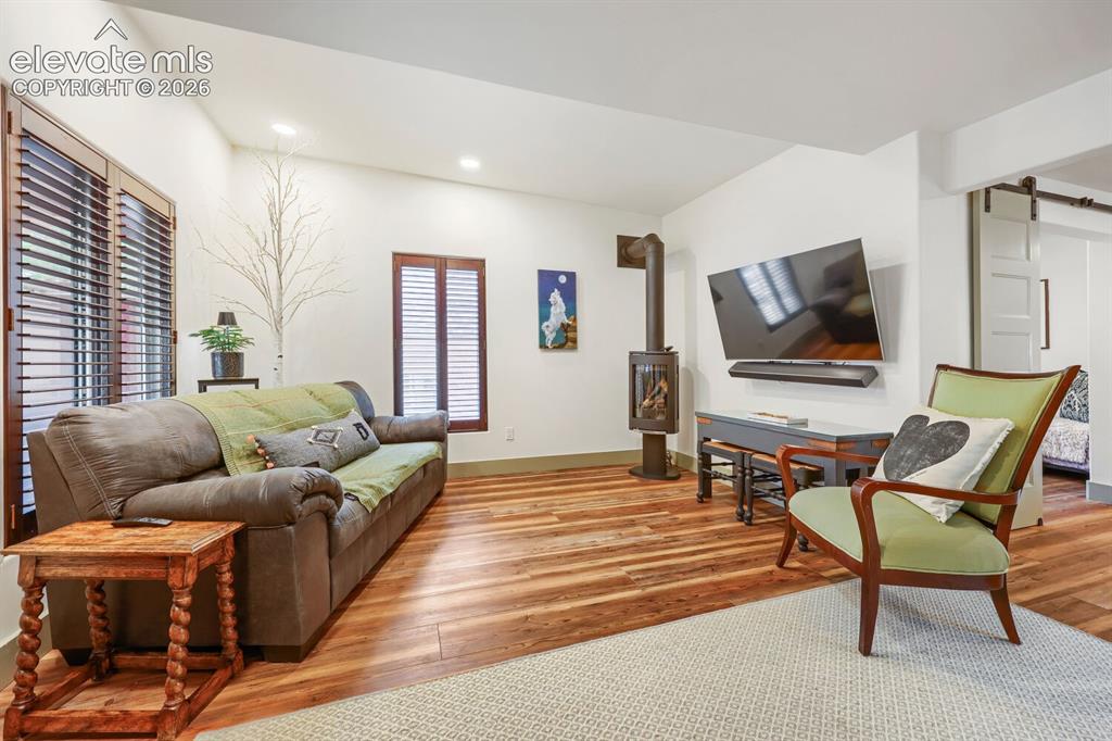Image 9 of 30: Wood-finish flooring, recessed lighting, and a modern wood-burning stove