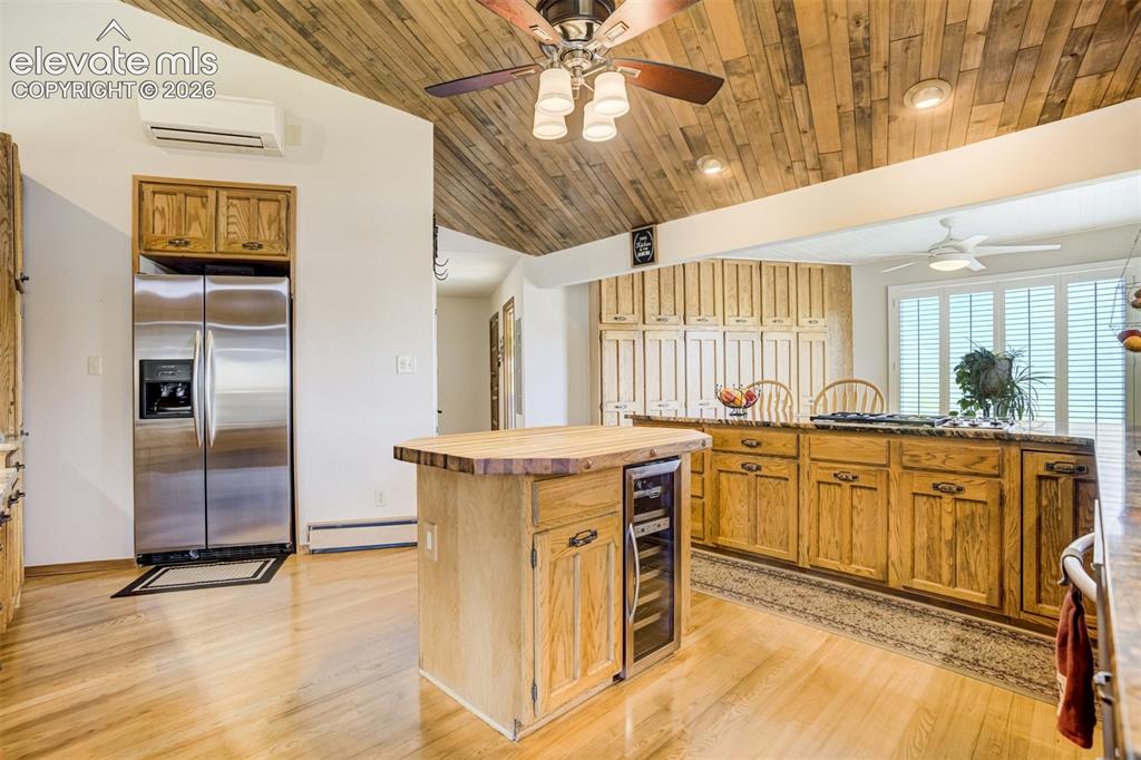 Image 14 of 50: Island, breakfast bar with gas stove top and pantry wall behind.