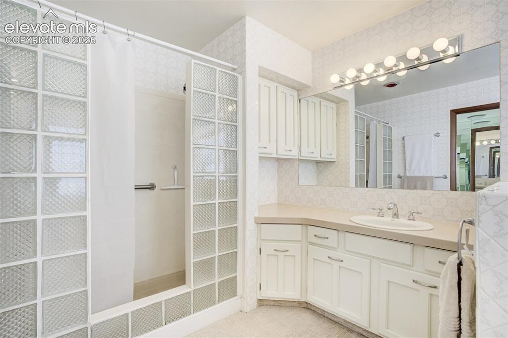 Image 26 of 50: Spa-like shower with glass block surround and second vanity.