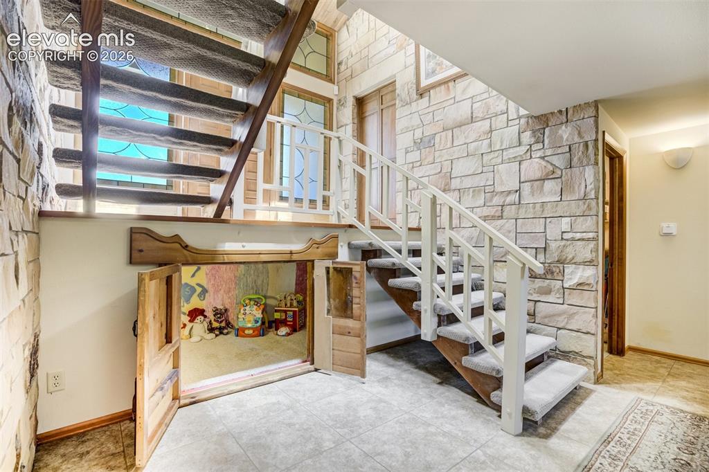 Image 33 of 50: Cubby under the stairs can be used for a reading/play spot or storage.