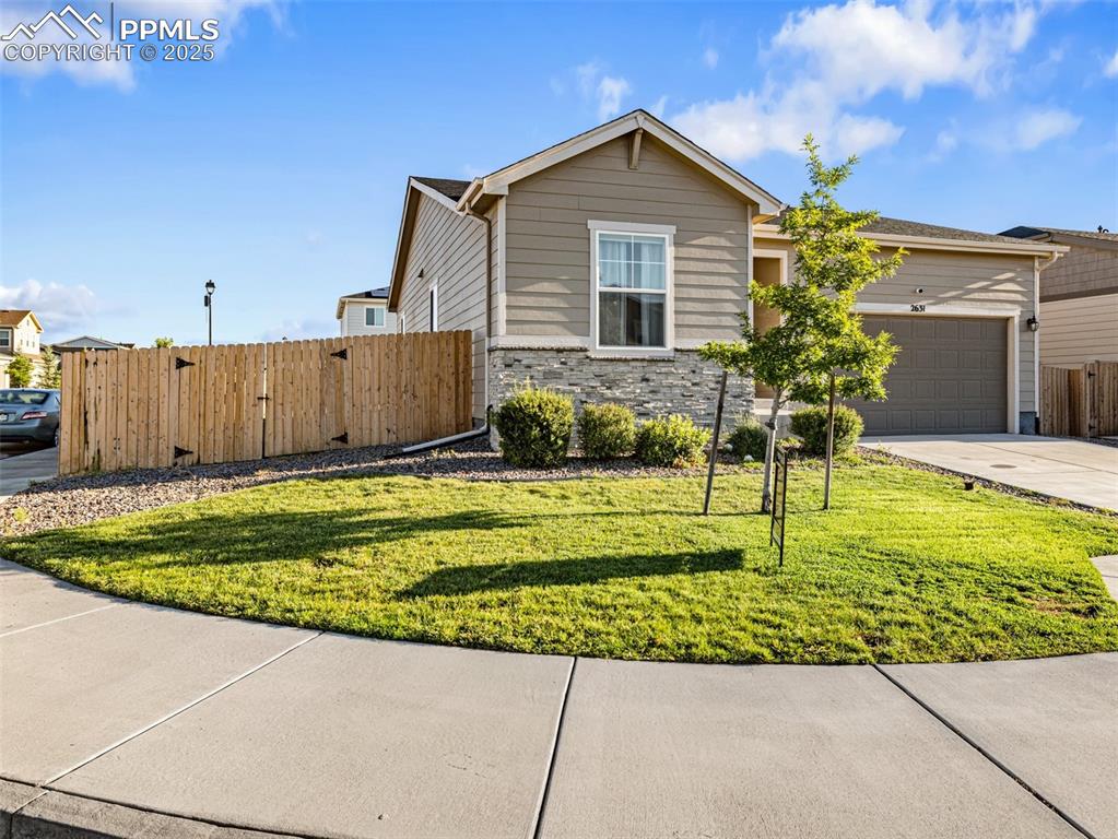 Caption: View of front of house with driveway, stone siding, and a garage