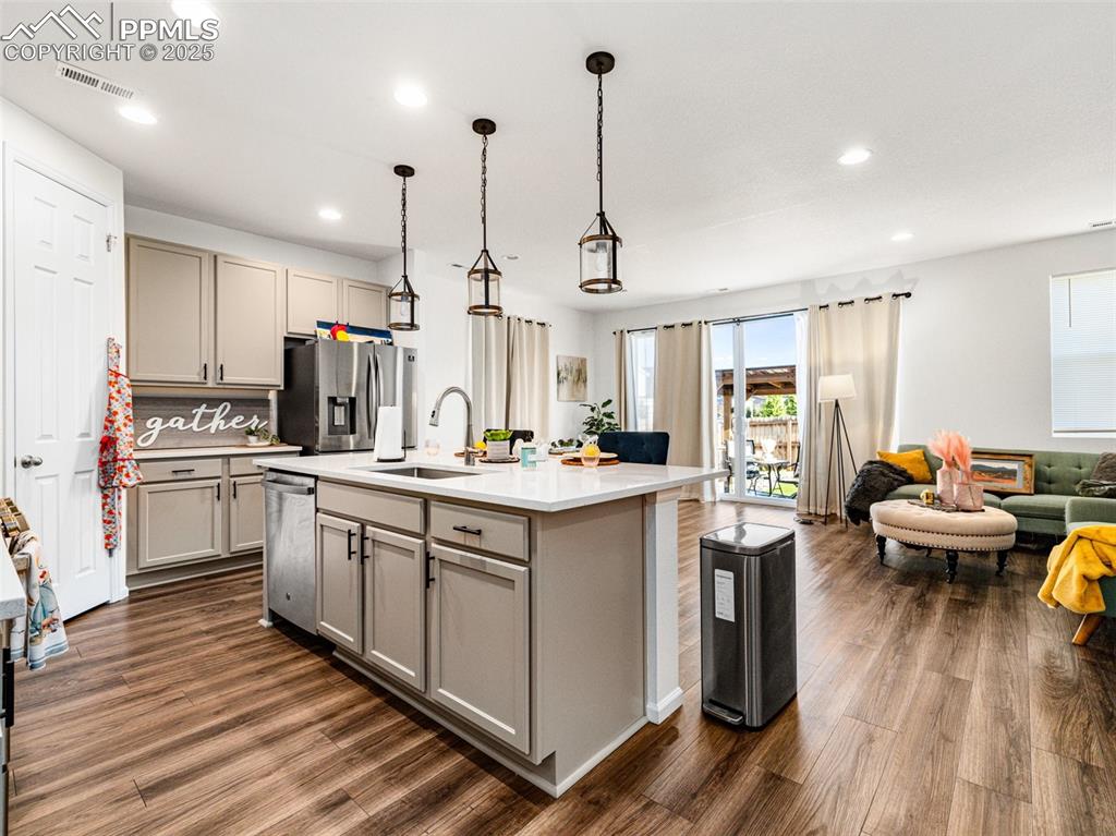 Image 10 of 26: Kitchen featuring gray cabinetry, open floor plan, pendant lighting, dark w