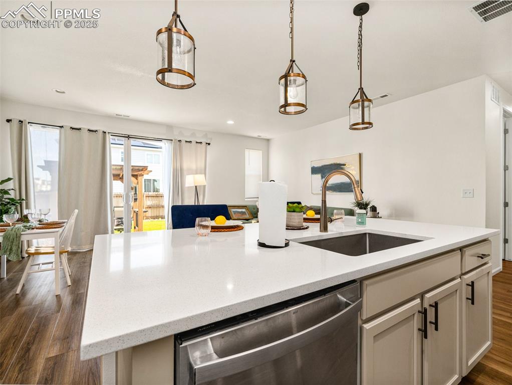 Image 11 of 26: Kitchen with dark wood finished floors, dishwasher, light stone counters, d