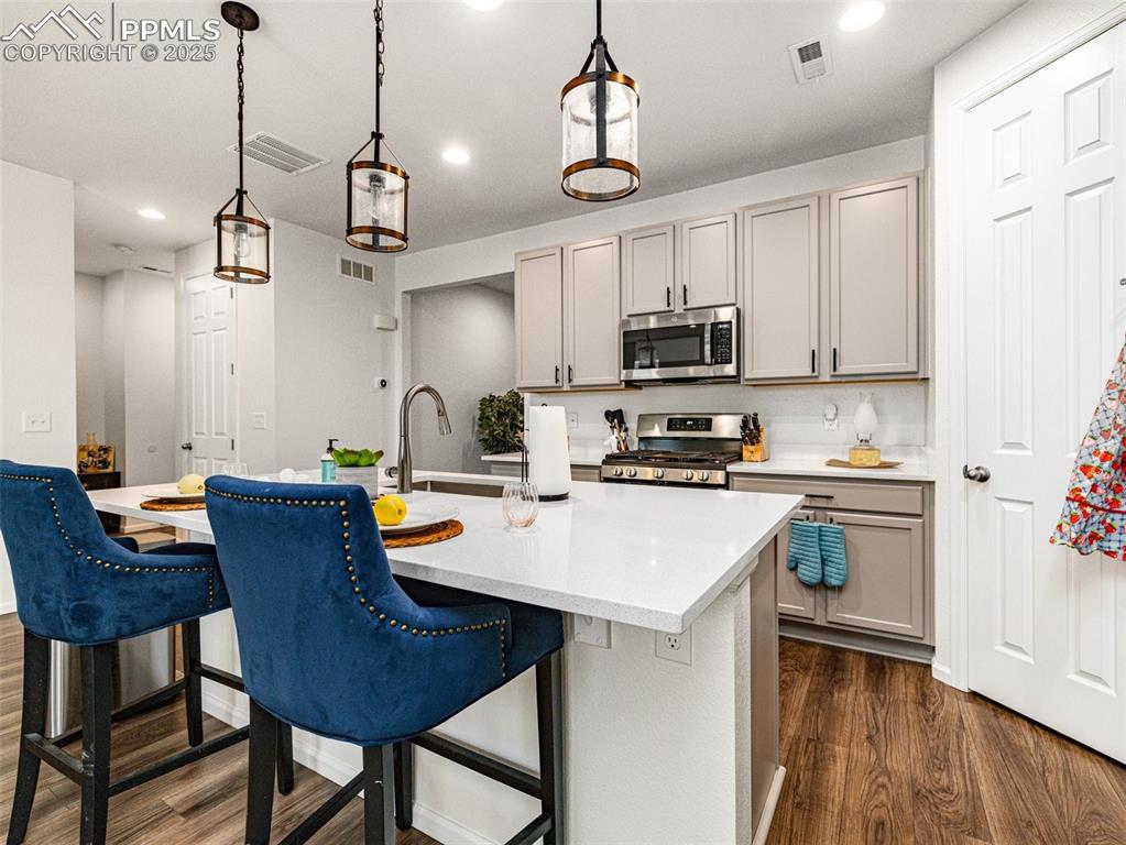 Image 12 of 26: Kitchen featuring dark wood finished floors, decorative light fixtures, rec