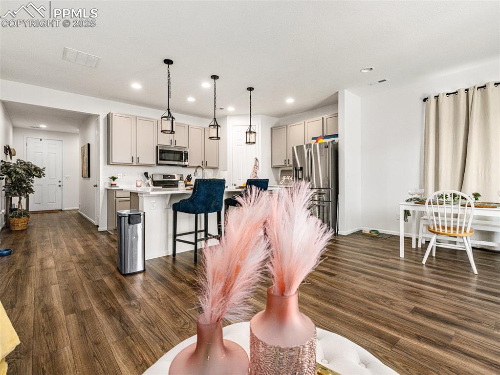 Image 17 of 26: Kitchen featuring decorative light fixtures, a breakfast bar, light counter