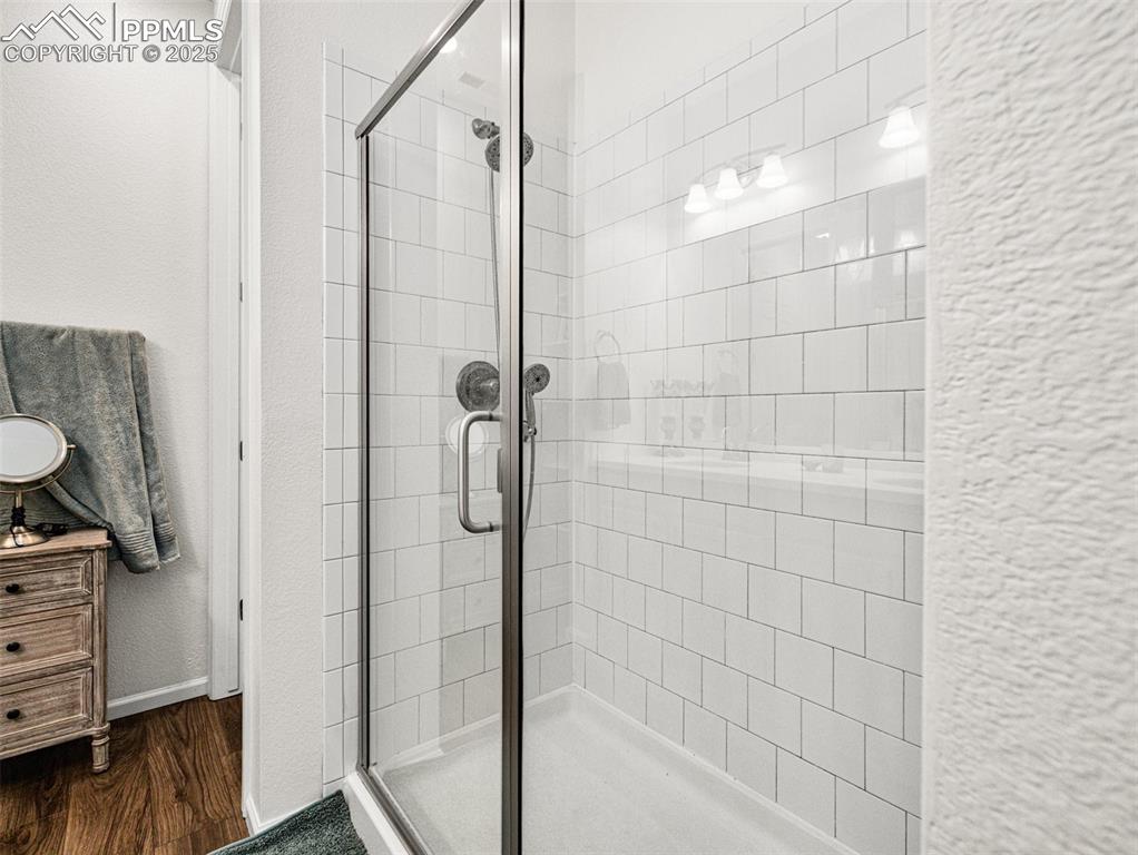 Image 22 of 26: Full bath with a stall shower, vanity, a textured wall, and dark wood-style