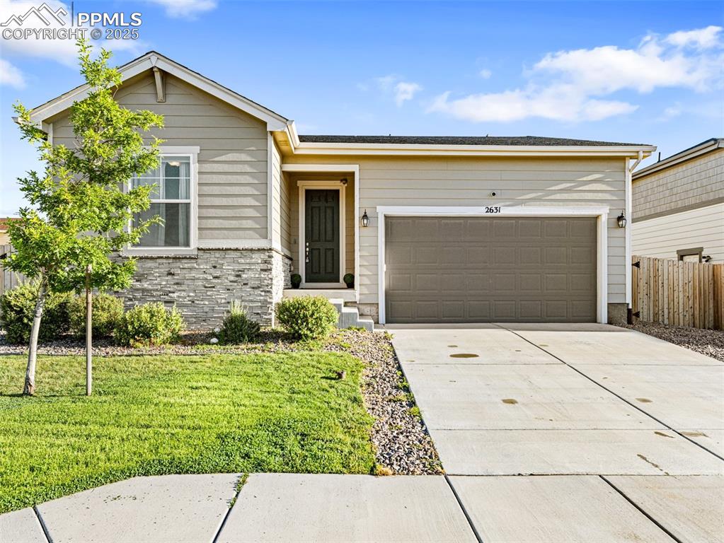Image 3 of 26: Ranch-style home featuring concrete driveway, stone siding, and an attached