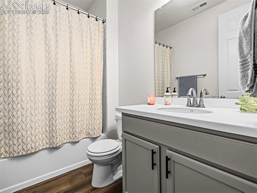 Image 6 of 26: Bathroom with vanity, dark wood-style flooring, and shower / tub combo with