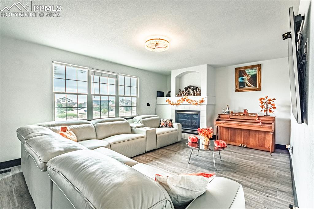Image 11 of 47: Living area with a textured ceiling, a tile fireplace, and wood finished fl