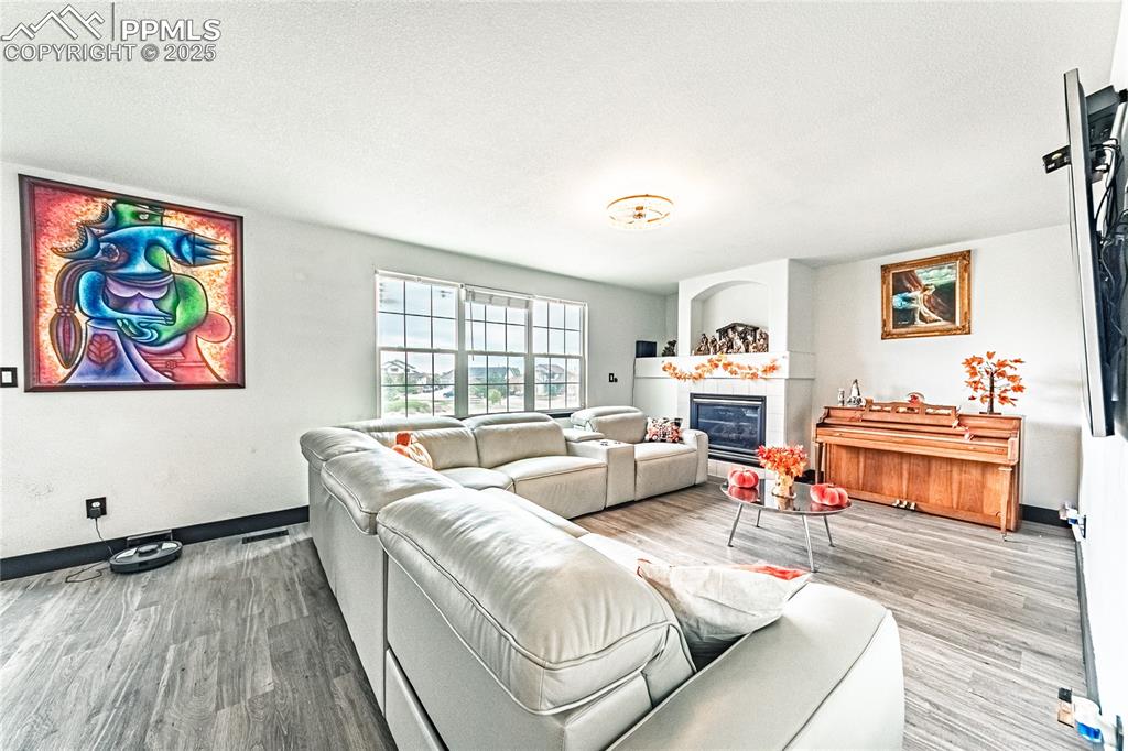 Image 12 of 47: Living room with a tile fireplace, wood finished floors, and a textured cei