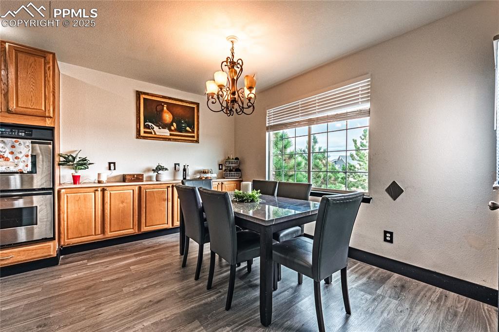 Image 15 of 47: Dining room with dark wood finished floors, a chandelier, and a textured wa