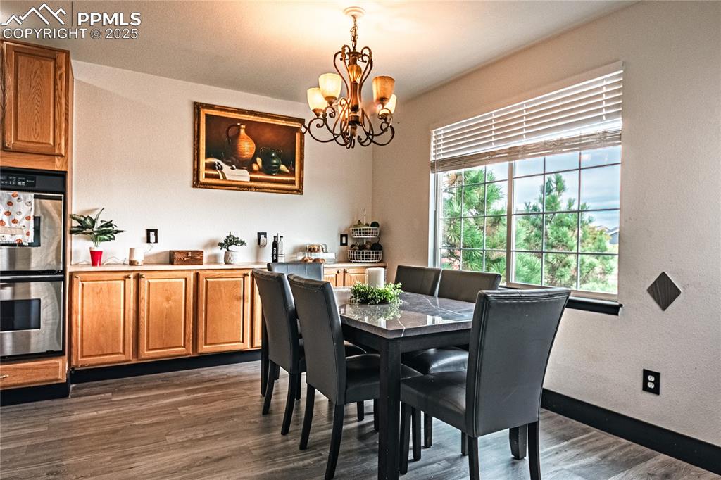 Image 16 of 47: Dining area featuring dark wood finished floors, a chandelier, and a textur