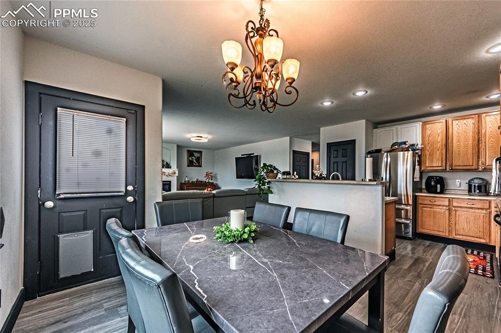 Image 17 of 47: Dining space with dark wood-style floors, a chandelier, and recessed lighti