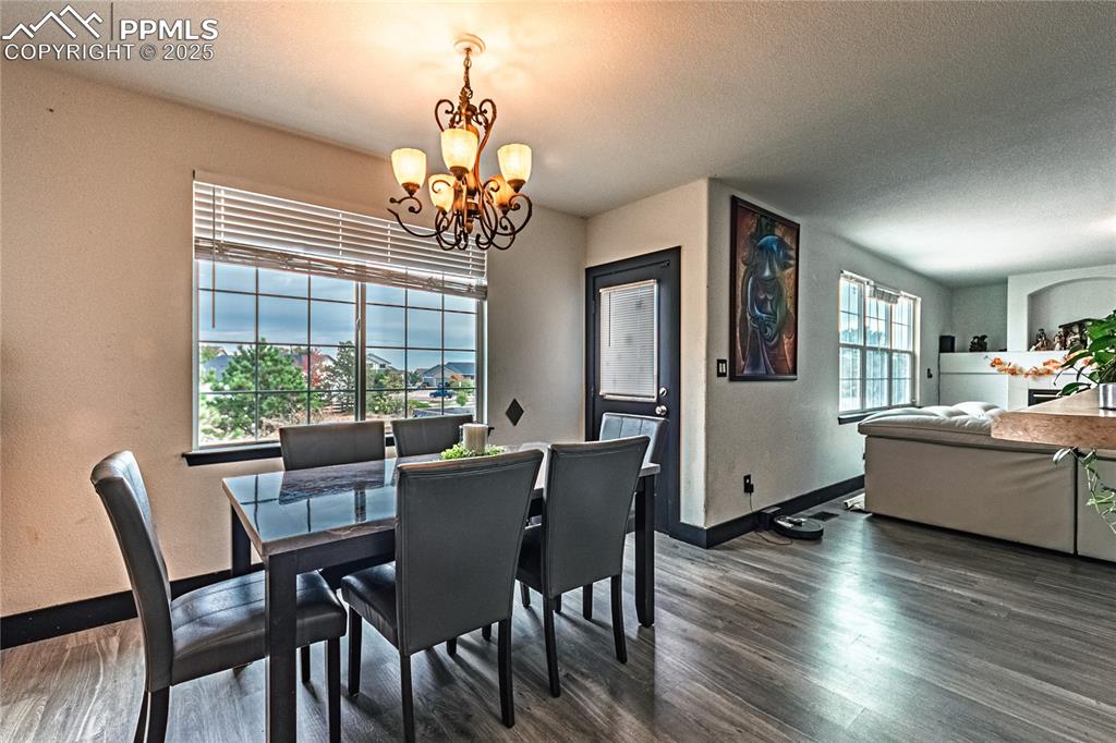Image 18 of 47: Dining area with a chandelier, a textured ceiling, dark wood-style flooring