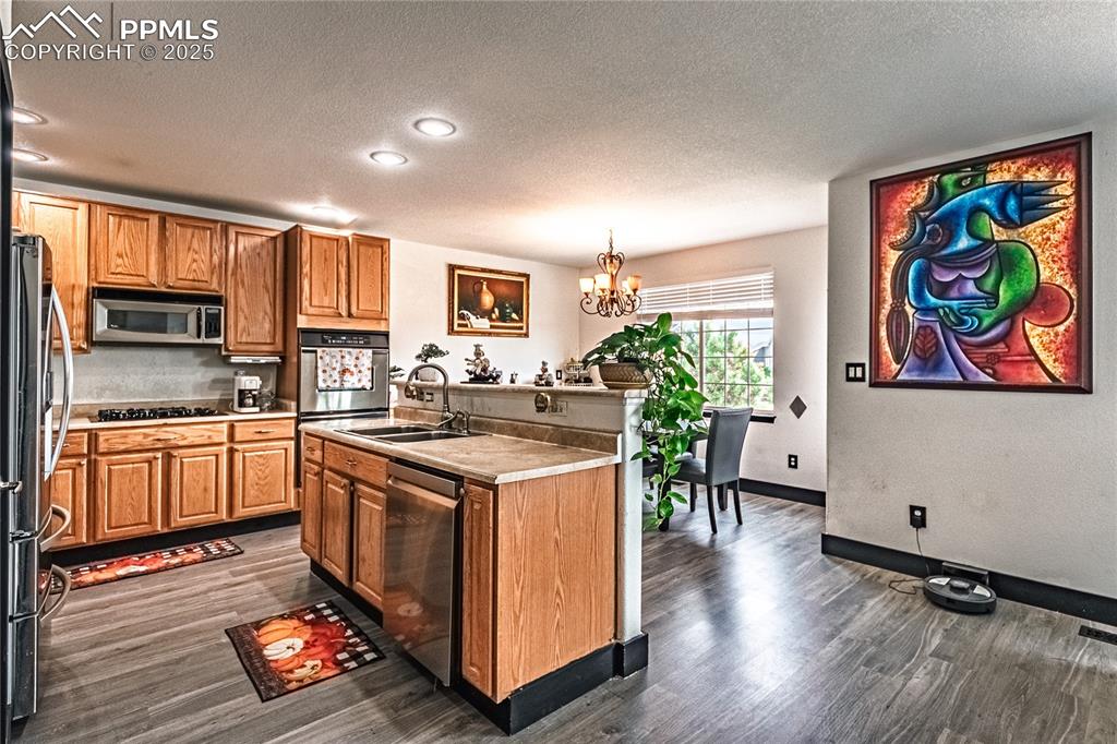 Image 20 of 47: Kitchen featuring a textured ceiling, stainless steel appliances, a chandel