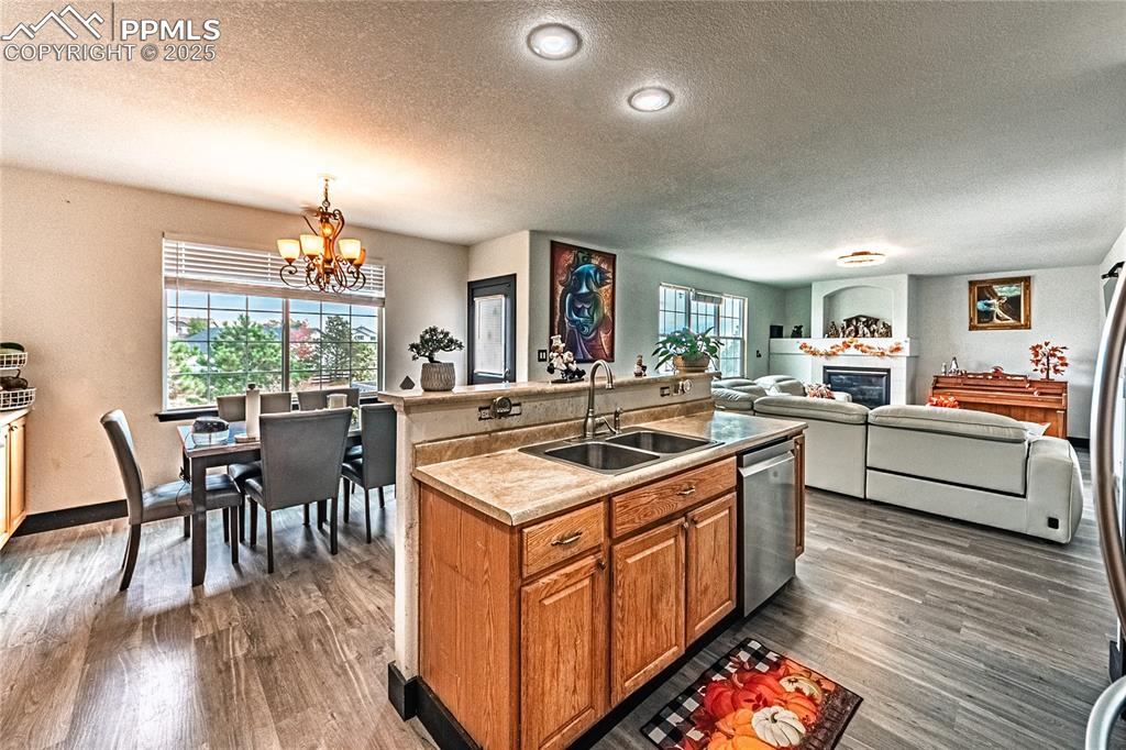 Image 23 of 47: Kitchen with brown cabinets, a textured ceiling, a kitchen island with sink
