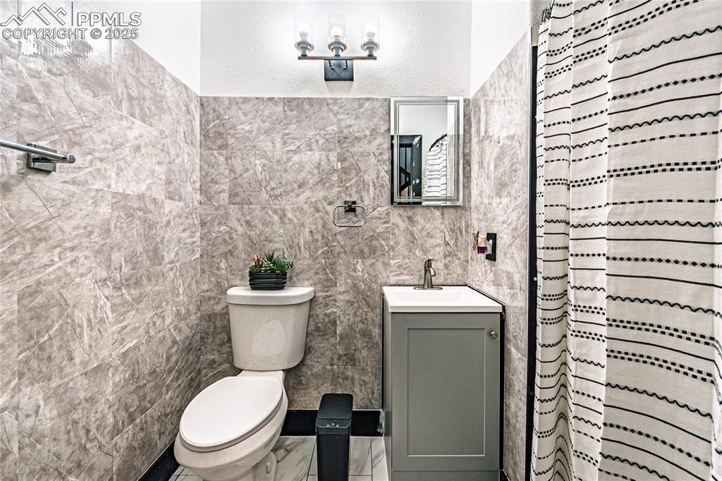 Image 25 of 47: Full bathroom with vanity, curtained shower, and tile walls