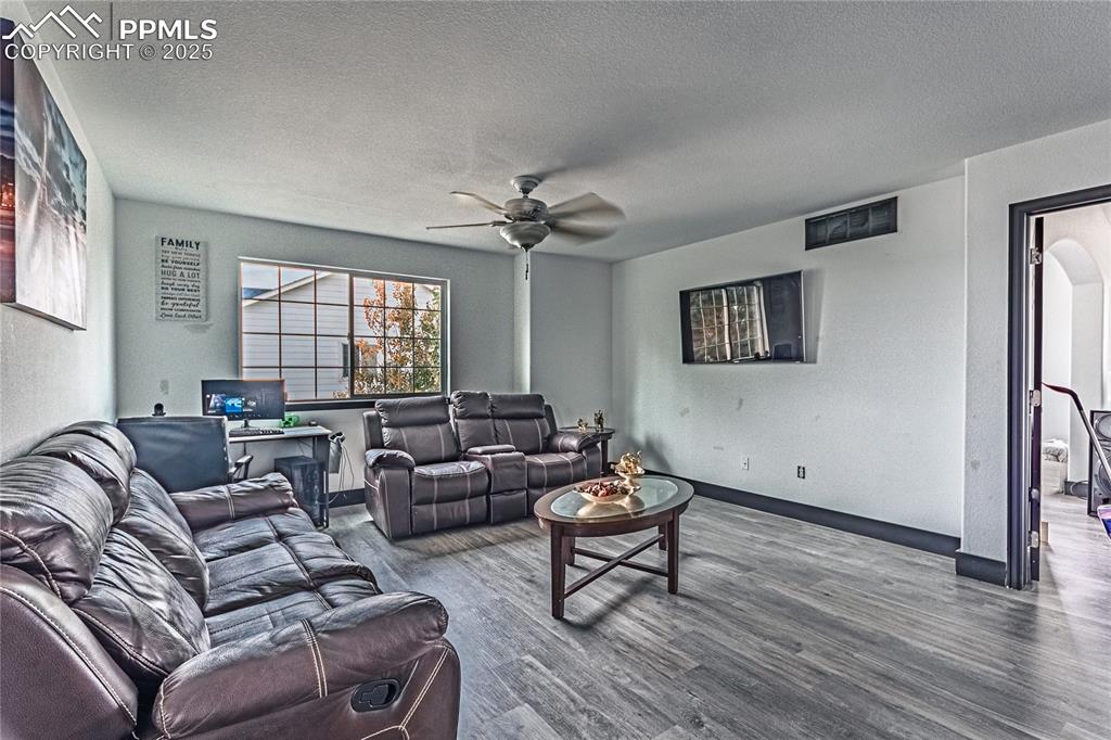 Image 29 of 47: Living area with wood finished floors, a textured ceiling, a ceiling fan, a