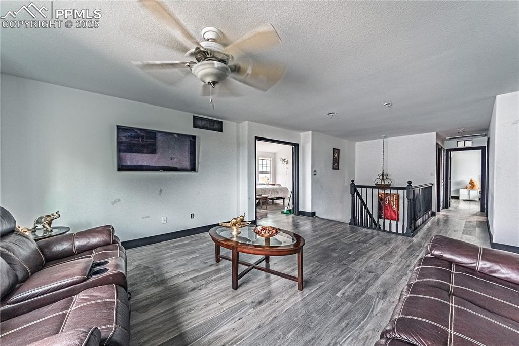 Image 31 of 47: Living room with wood finished floors, a textured ceiling, and ceiling fan