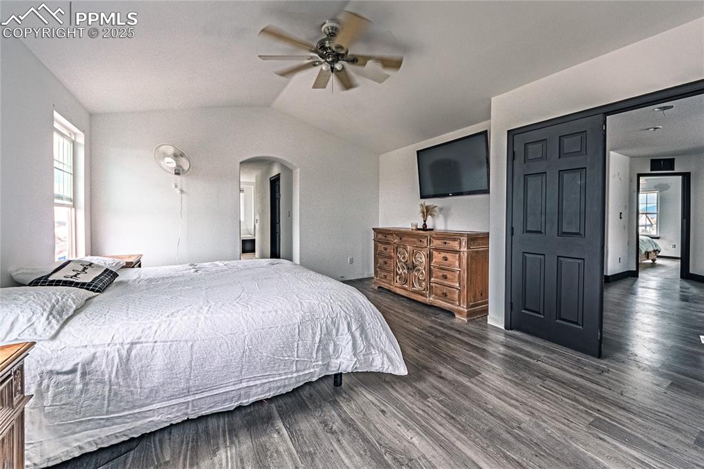 Image 34 of 47: Bedroom featuring vaulted ceiling, wood finished floors, ceiling fan, and a