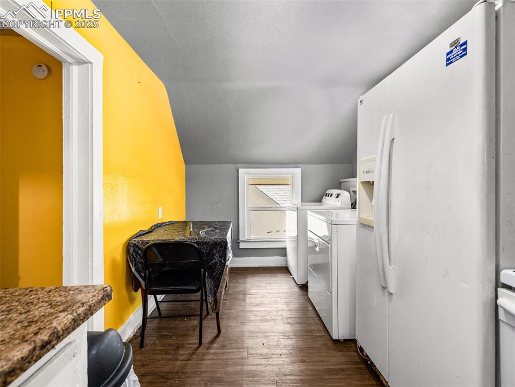 Image 10 of 30: Kitchen with white fridge with ice dispenser, white cabinetry, vaulted ceil