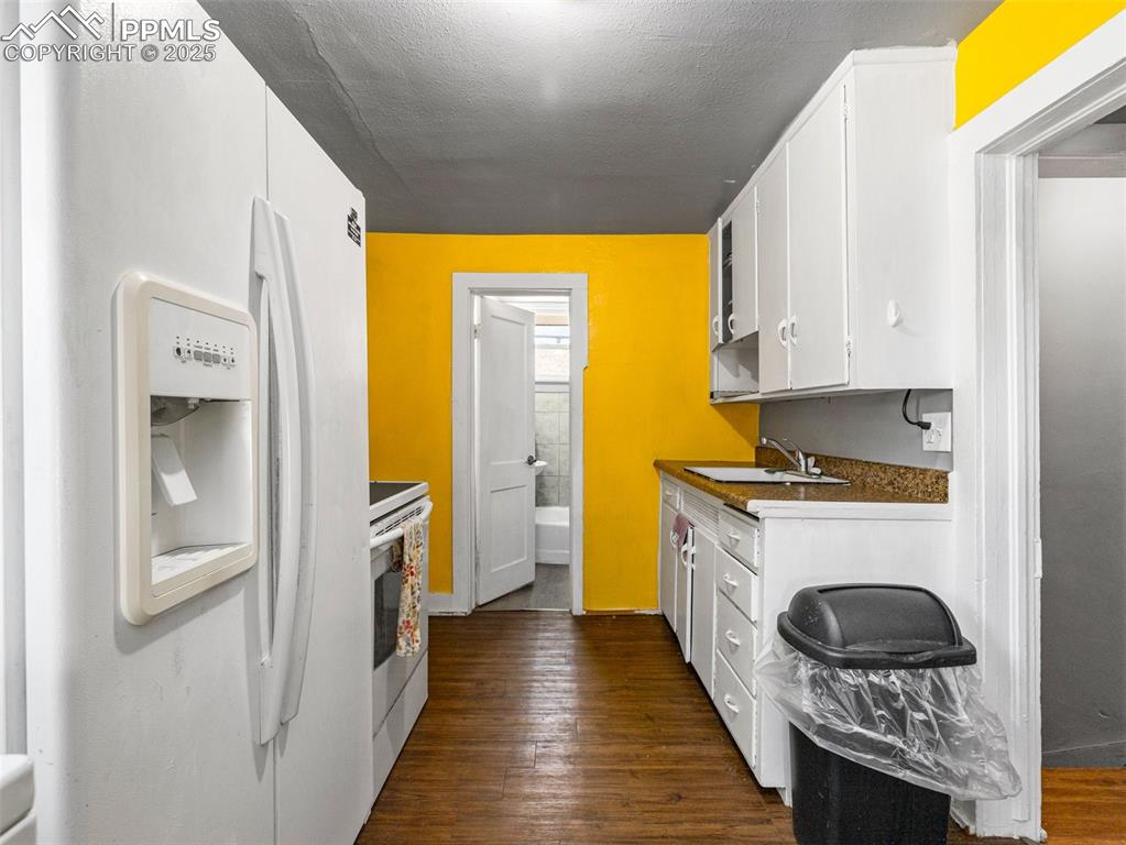 Image 11 of 30: Kitchen featuring white cabinetry, white appliances, dark wood-style floors