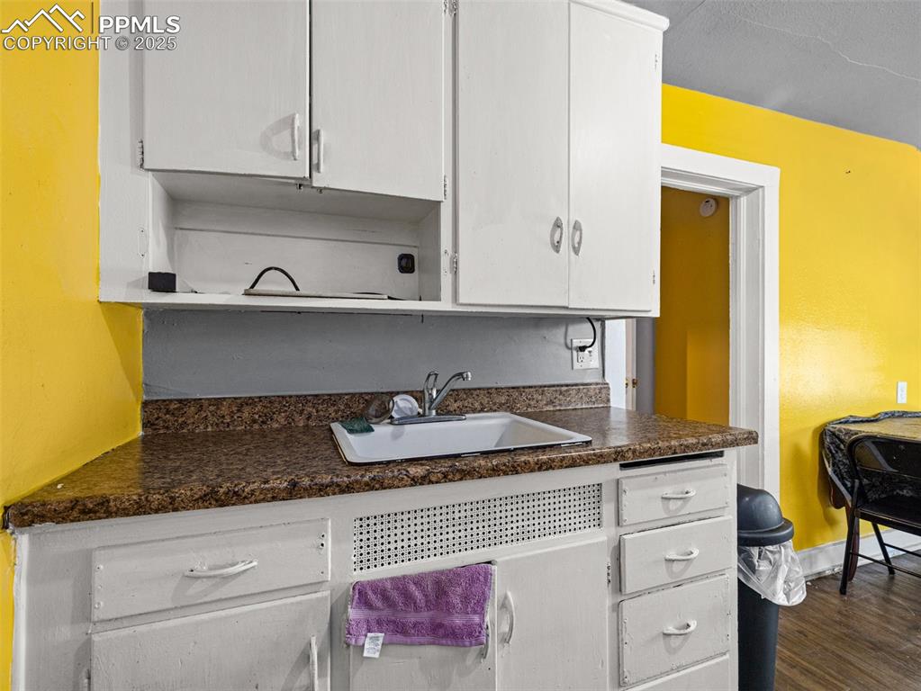 Image 13 of 30: Kitchen with dark countertops, white cabinets, and dark wood-type flooring