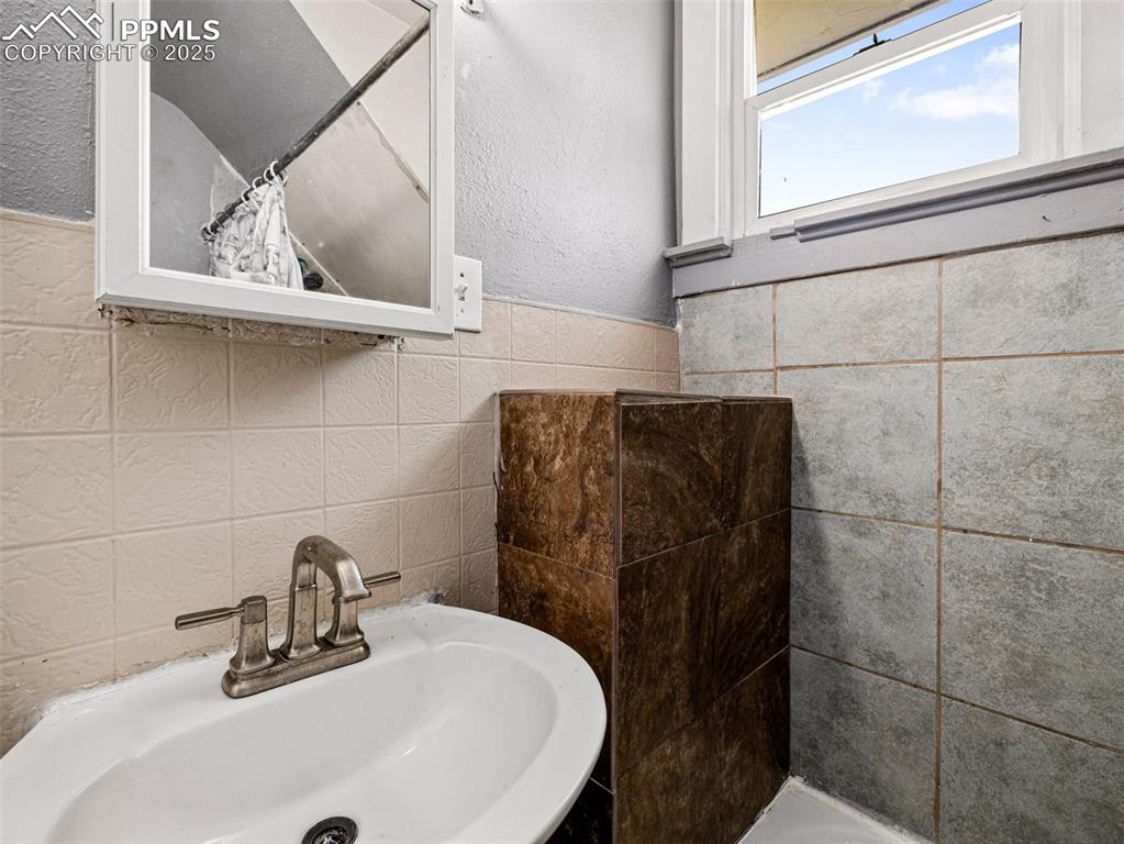 Image 14 of 30: Bathroom with tile walls, a textured wall, a shower with curtain, and a wai