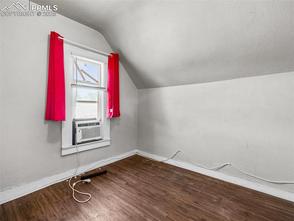 Image 16 of 30: Bonus room featuring dark wood-type flooring, vaulted ceiling, a textured c