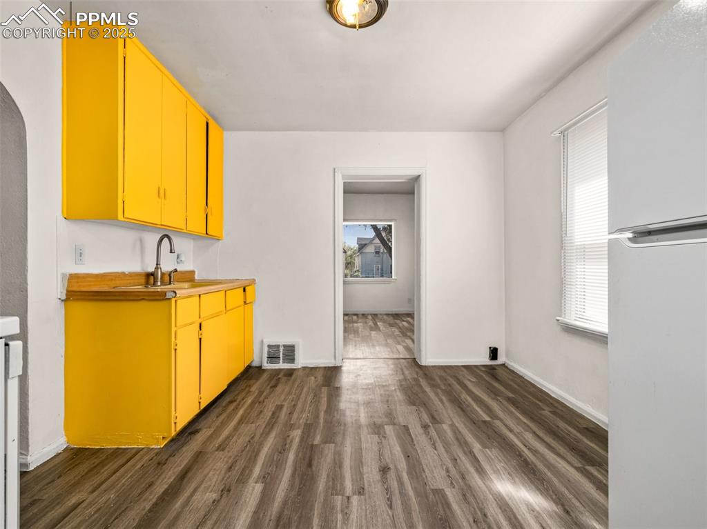 Image 23 of 30: Bar featuring freestanding refrigerator, dark wood-style floors, light coun