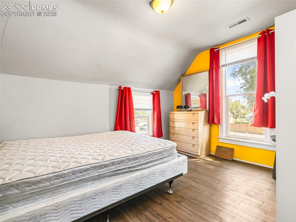 Image 5 of 30: Bedroom featuring wood finished floors and lofted ceiling