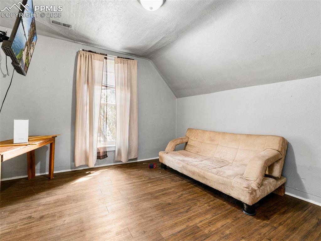 Image 7 of 30: Sitting room featuring wood finished floors, a textured ceiling, and vaulte