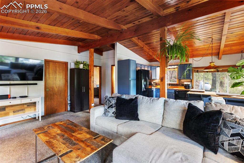 Image 13 of 46: Open living room featuring wooden ceiling open to kitchen area