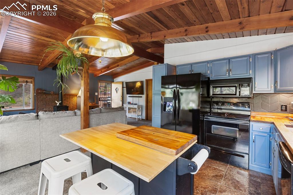 Image 14 of 46: Kitchen featuring wood counters, open floor plan, blue cabinets, black appl
