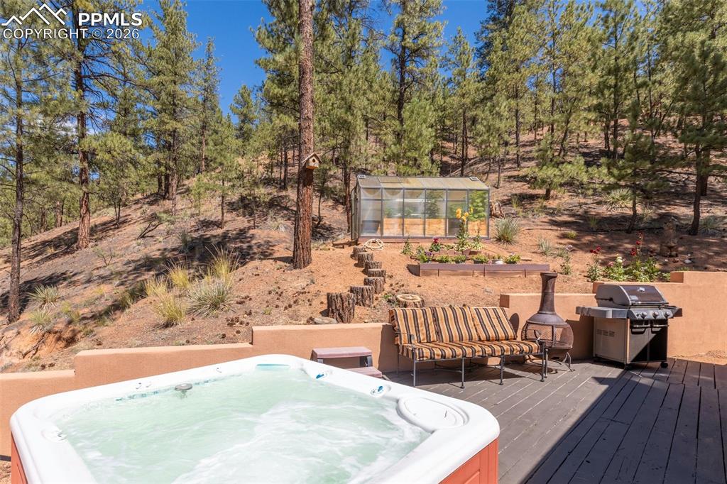 Image 36 of 46: Wooden deck featuring a hot tub, sitting area and greenhouse