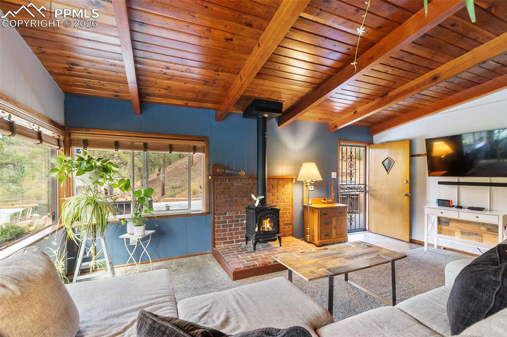Image 4 of 46: Cozy living room with gas stove and beame ceiling