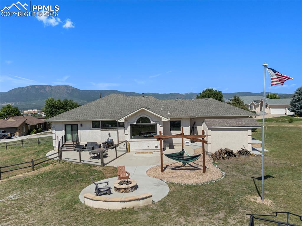 Image 15 of 47: Back of property with a patio area, a fire pit, a mountain view, and roof w