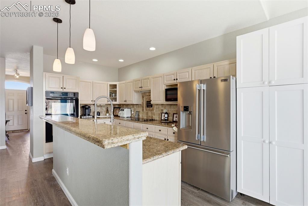 Image 23 of 47: Kitchen with stone pendant lighting, a kitchen island with sink, light ston