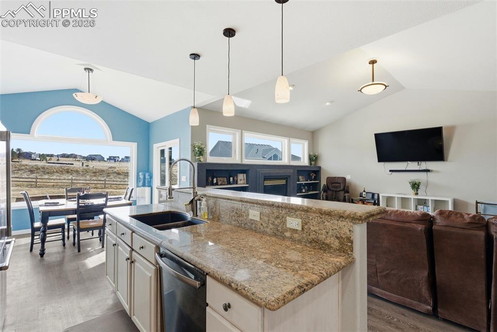 Image 27 of 47: Kitchen featuring light stone counters, open floor plan, a fireplace, and a
