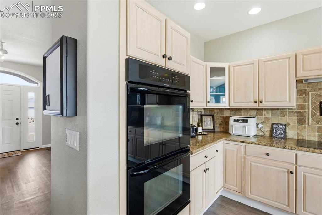 Image 29 of 47: Kitchen featuring grey plank floors, tasteful backsplash, dark granite coun