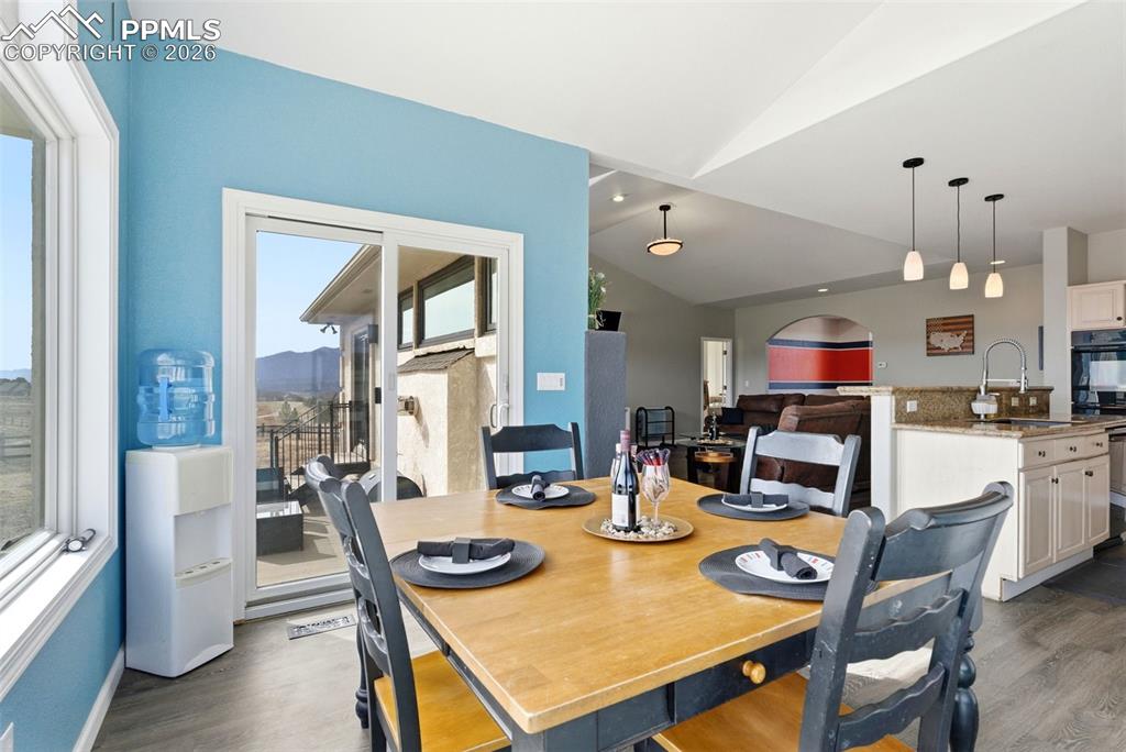 Image 32 of 47: In kitchen Dining space with vaulted ceiling and grey plank flooring