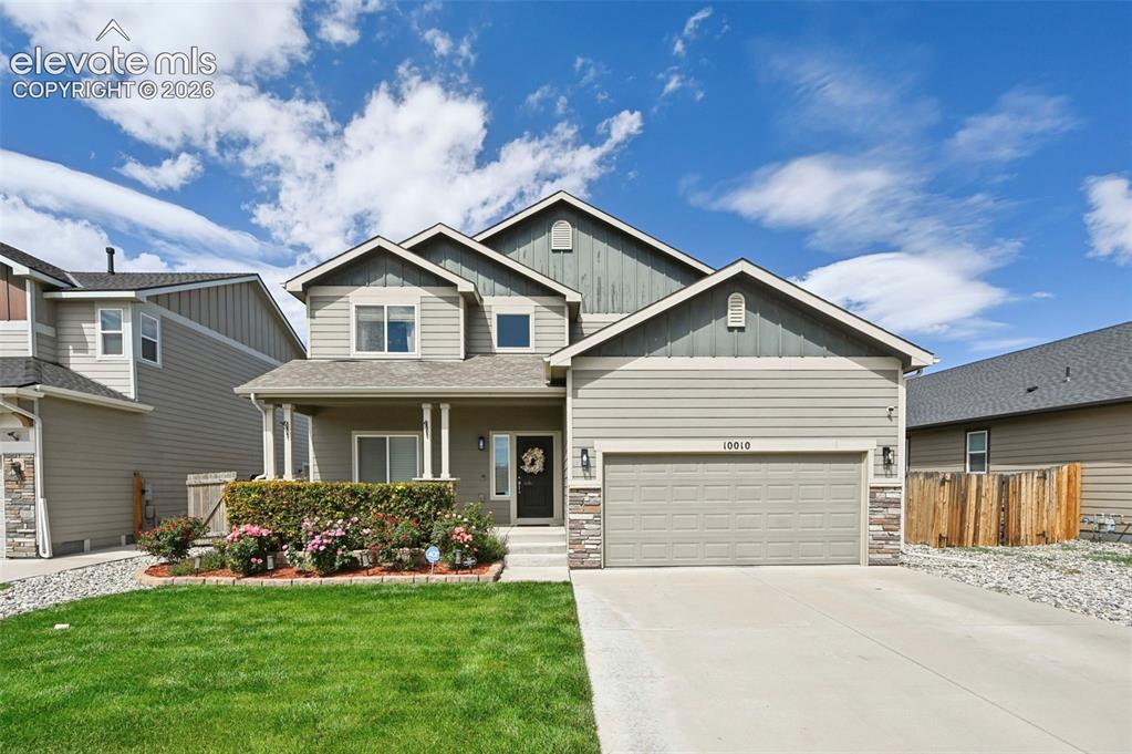 Caption: Two-story residence featuring a covered front porch with decorative columns, a concrete driveway, an