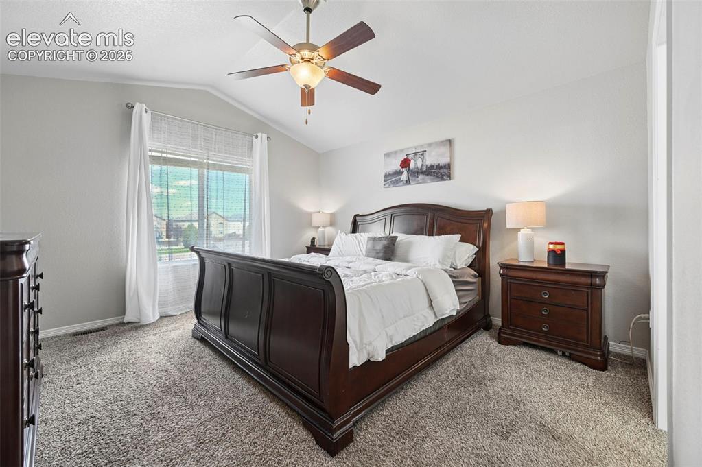 Image 11 of 29: Vaulted ceiling, ceiling fan with light fixture, large window, neutral wall