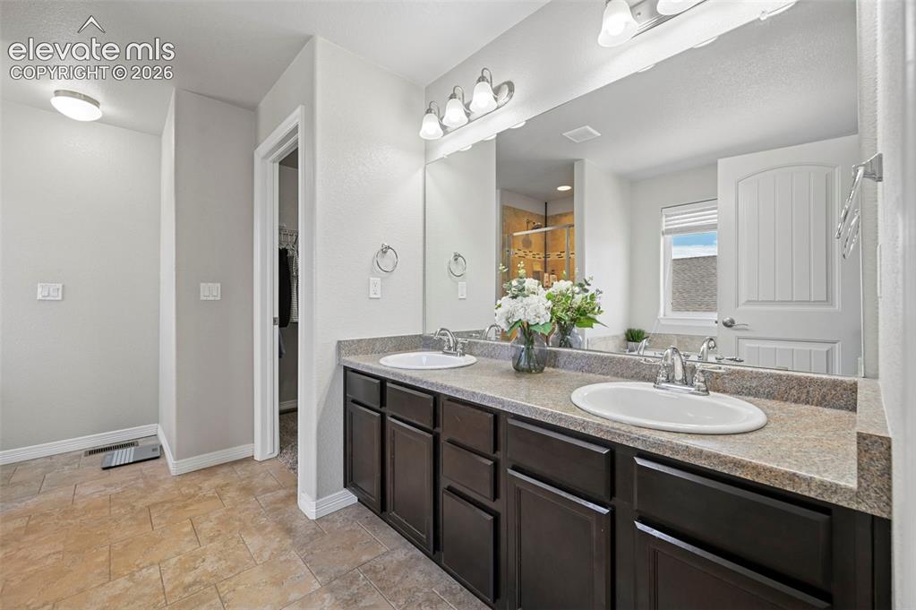 Image 13 of 29: Dual sink vanity with dark wood-finish cabinetry, light-toned countertop, a